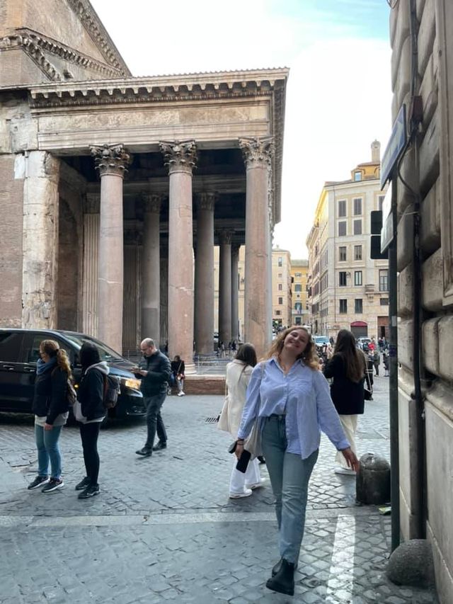 Young woman standing confidently alone at Rome's Pantheon, surrounded by tourists