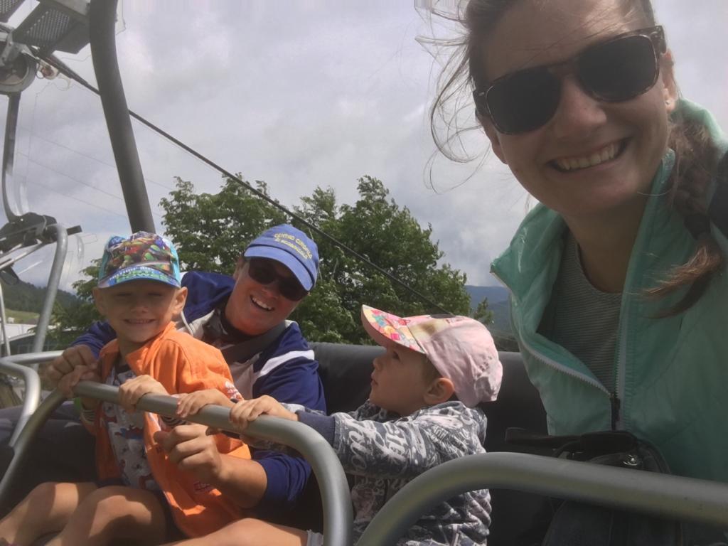 Au pair smiling with three children during a mountain outing.