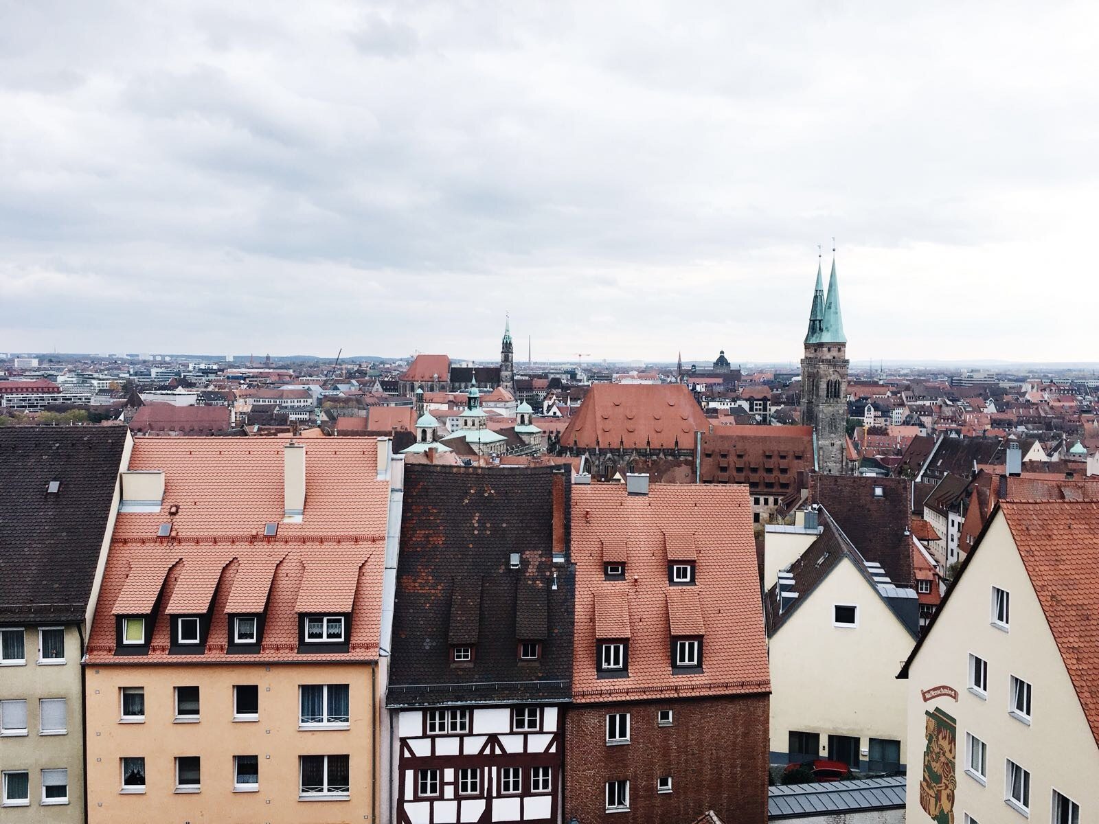 Aerial view of a historic European city with red terracotta roofs and Gothic church spires.