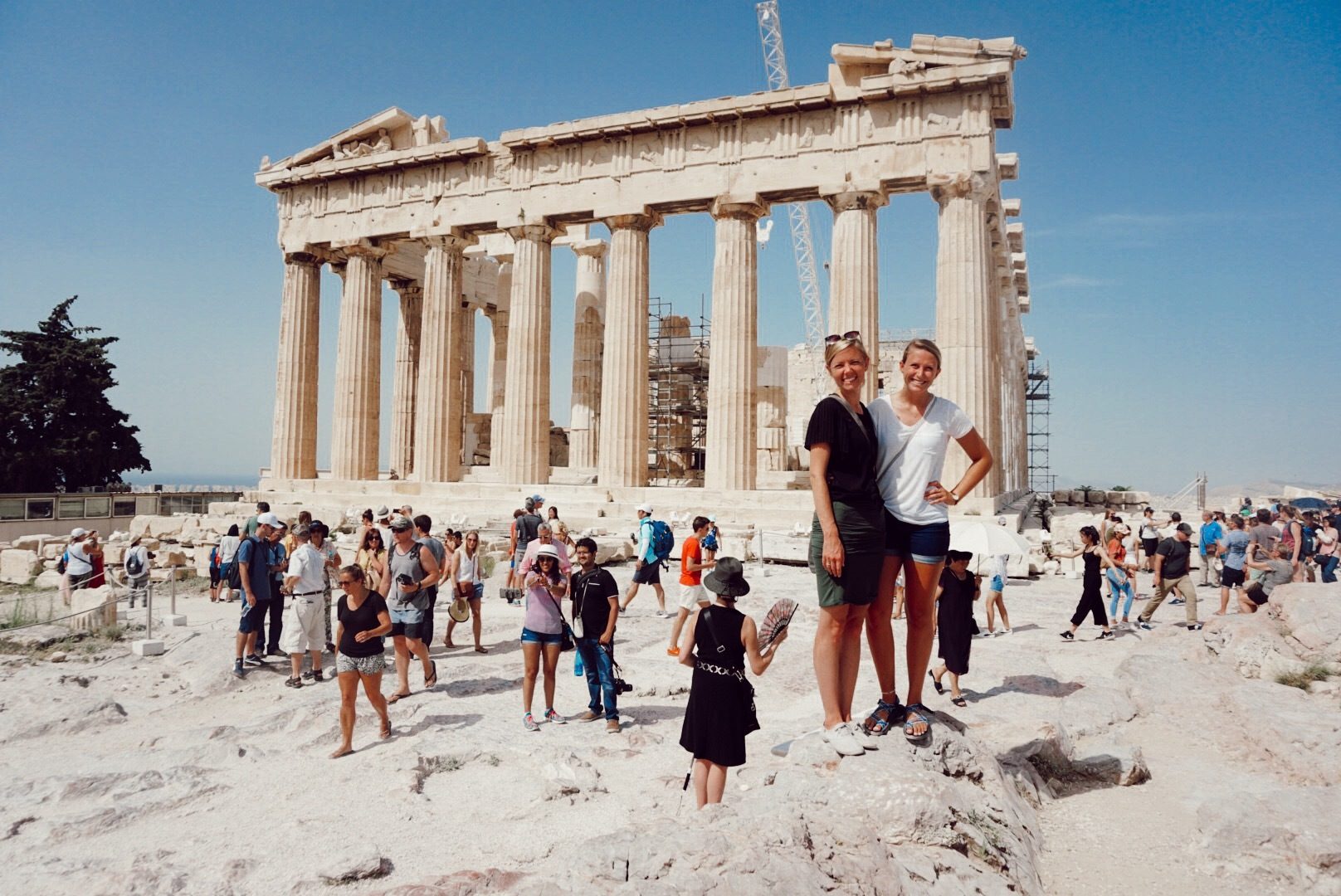 Two smiling young women at the Parthenon in Athens during their travels.