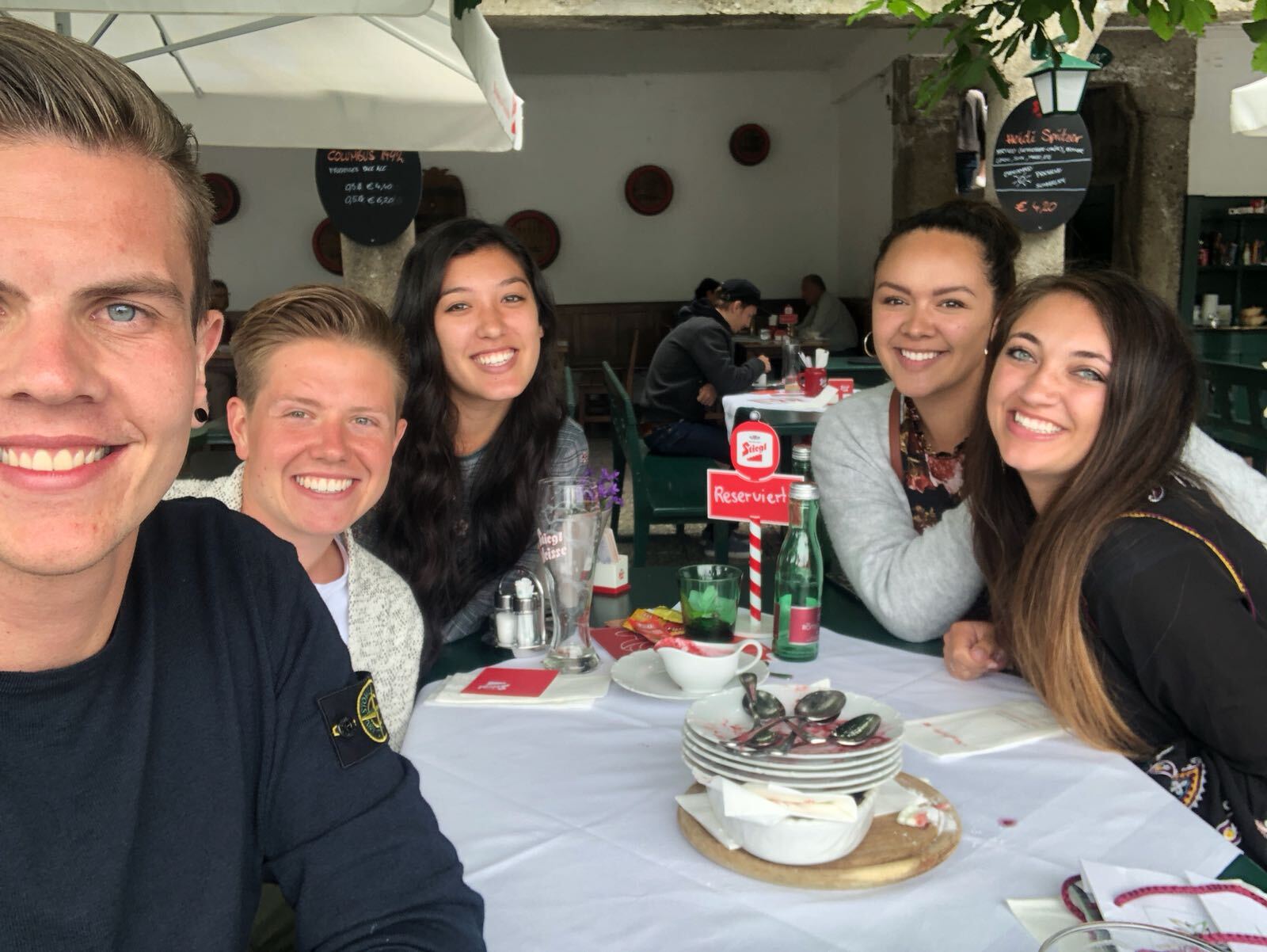 Friends gathered around a restaurant table, smiling during a shared meal.