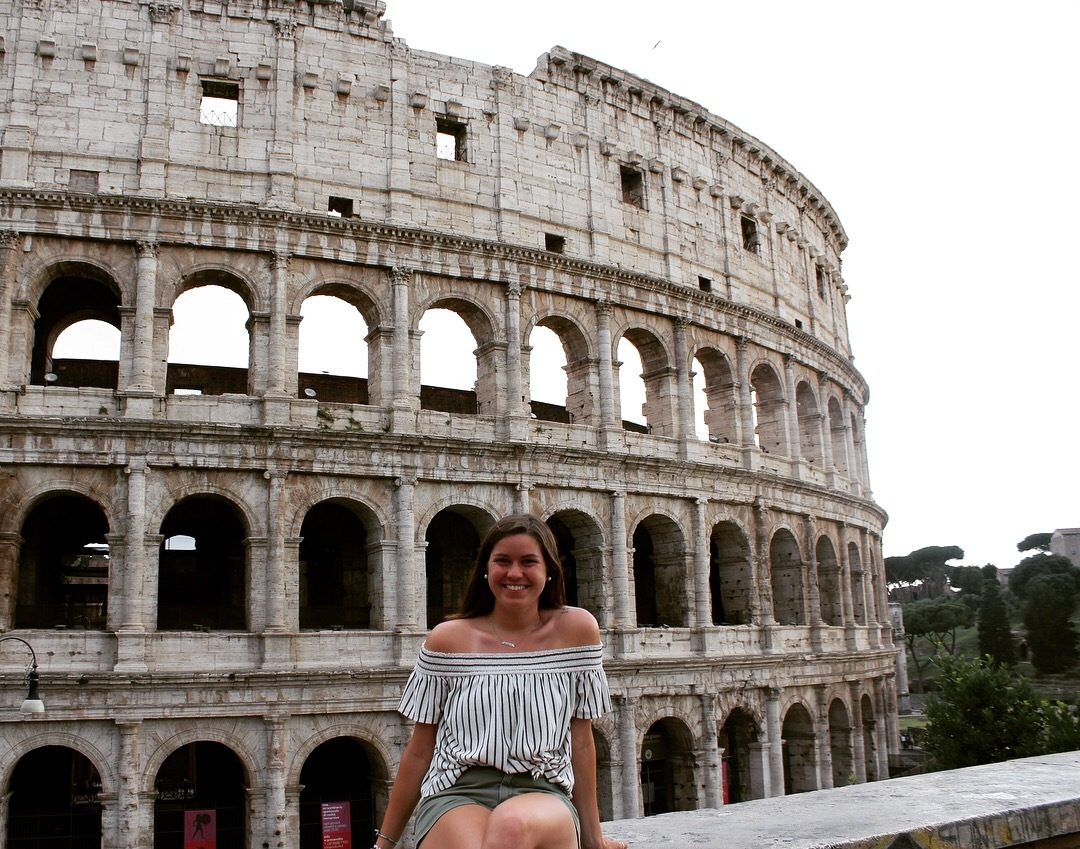 Young woman smiling at the Roman Colosseum in Rome, Italy.