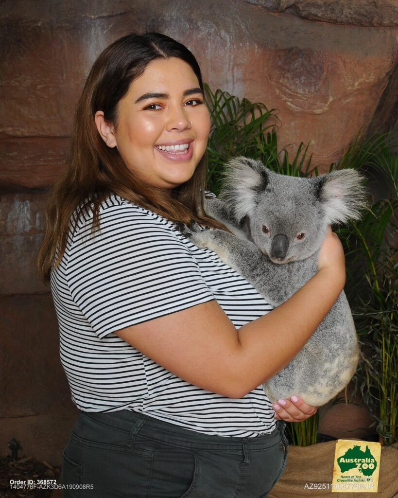 Young woman smiling while holding a koala at Australia Zoo.