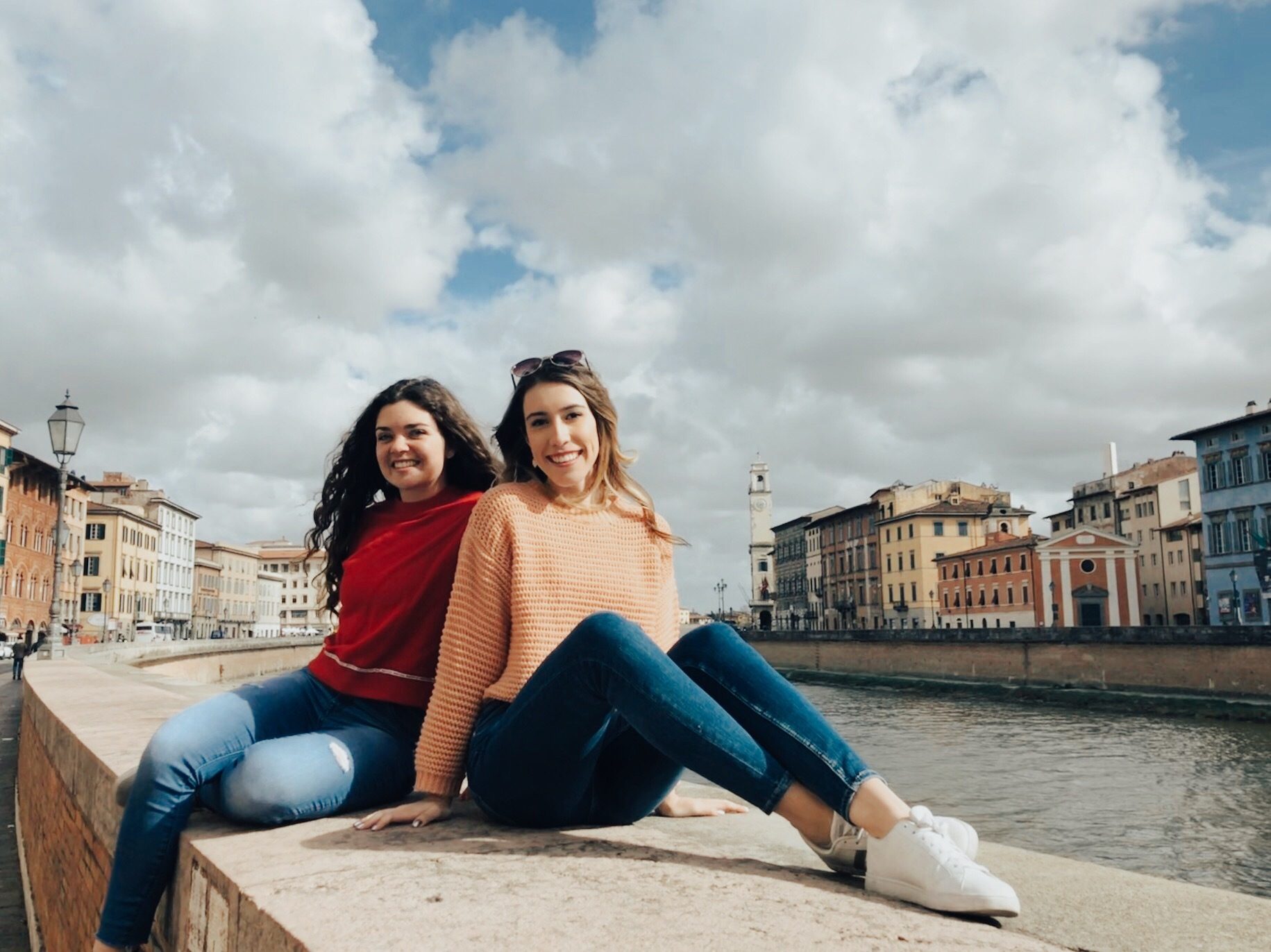Two young women enjoying a moment by the Arno River in Pisa, Italy.